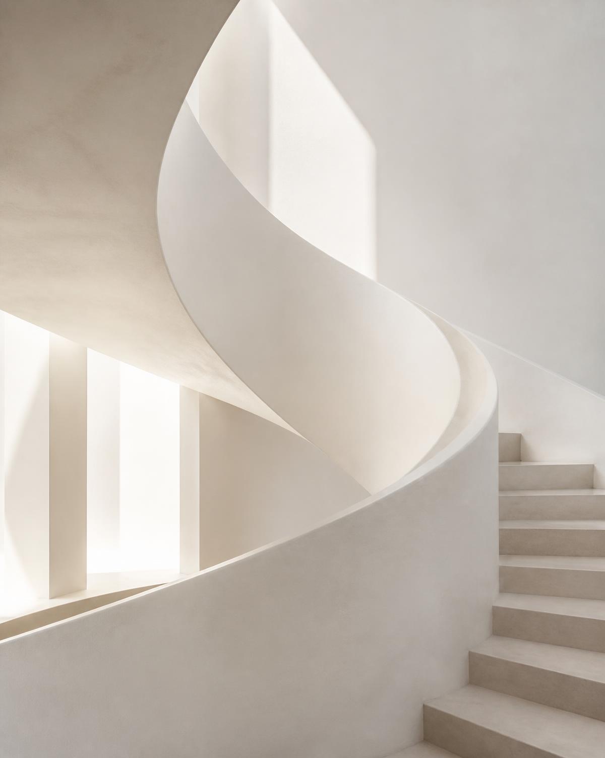 Soft daylight falling across a curved white concrete staircase